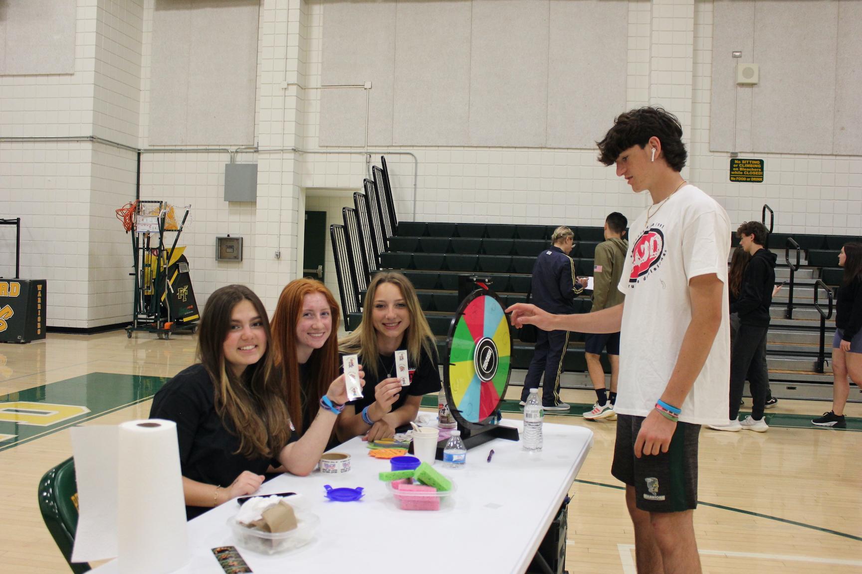 Ian Temple spins the wheels to win a temporary tattoo from Brooklyn Harrison, Gabby Michael, Rease Solomon