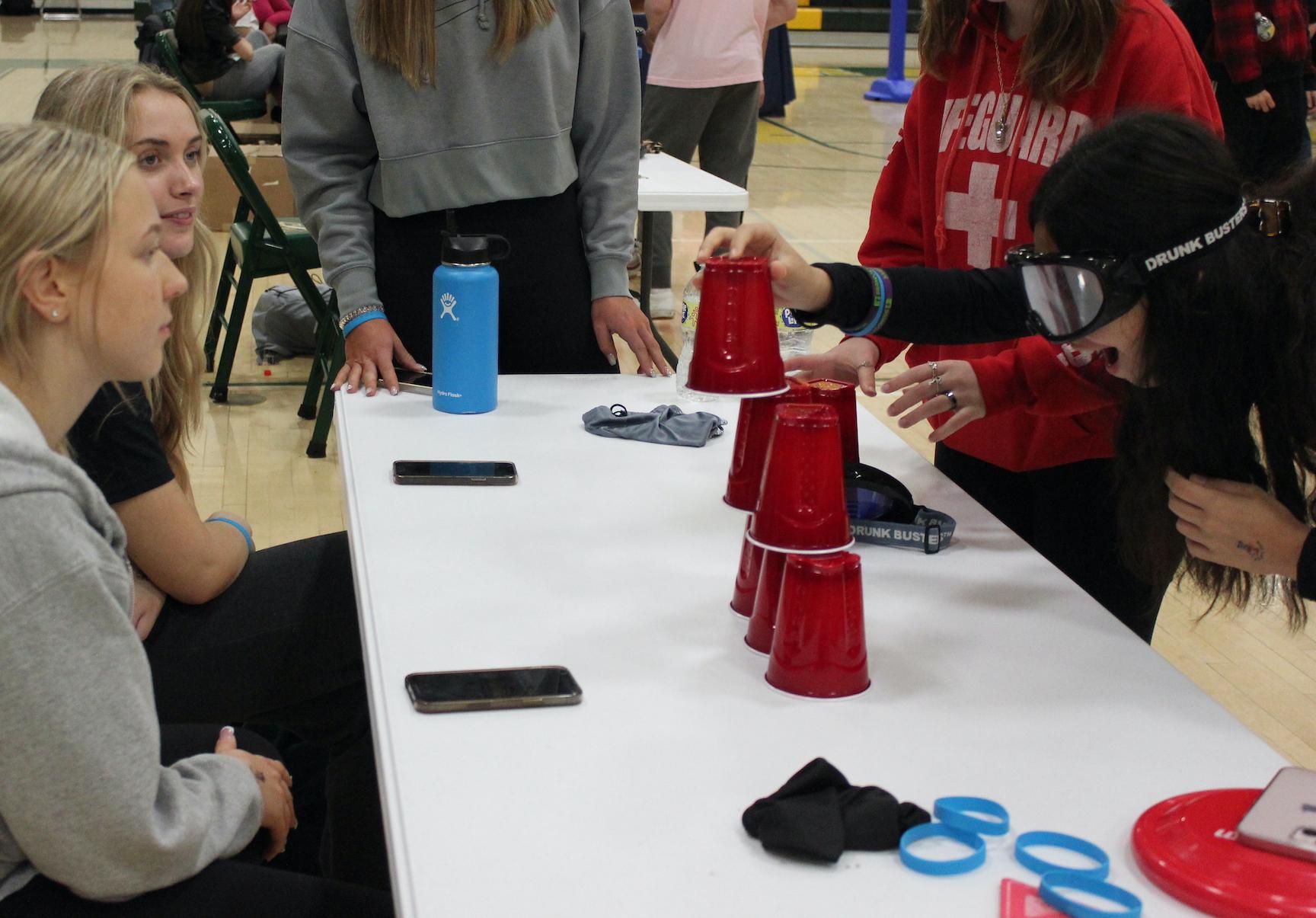 Leah Kaczmarkiewicz and Maggie Bart watch as Gianna Escobar attempts to stack cups