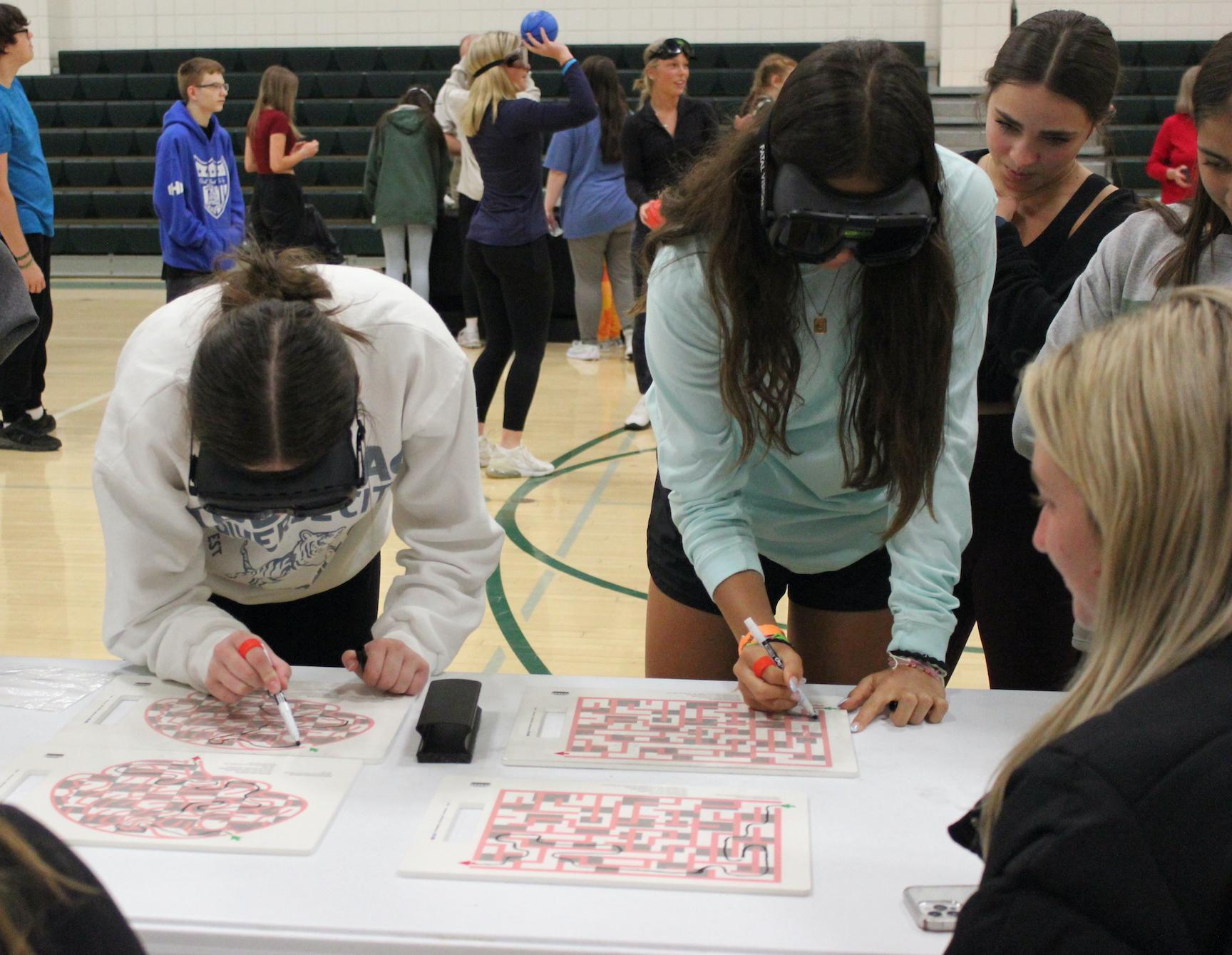 Emma Young, Cheyenne Juarez, and Lauren Yankes attempt to complete a maze while wearing the simulation goggles