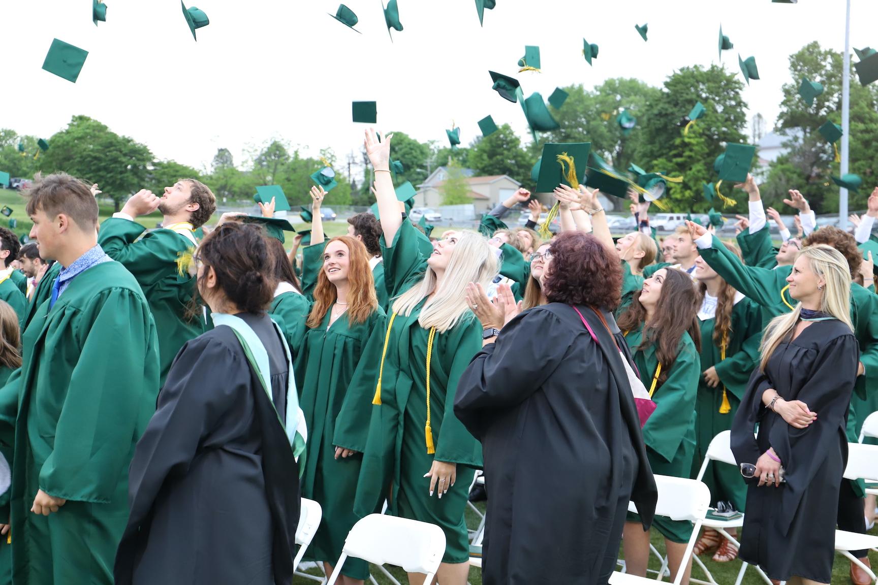 students toss their graduation caps in the air