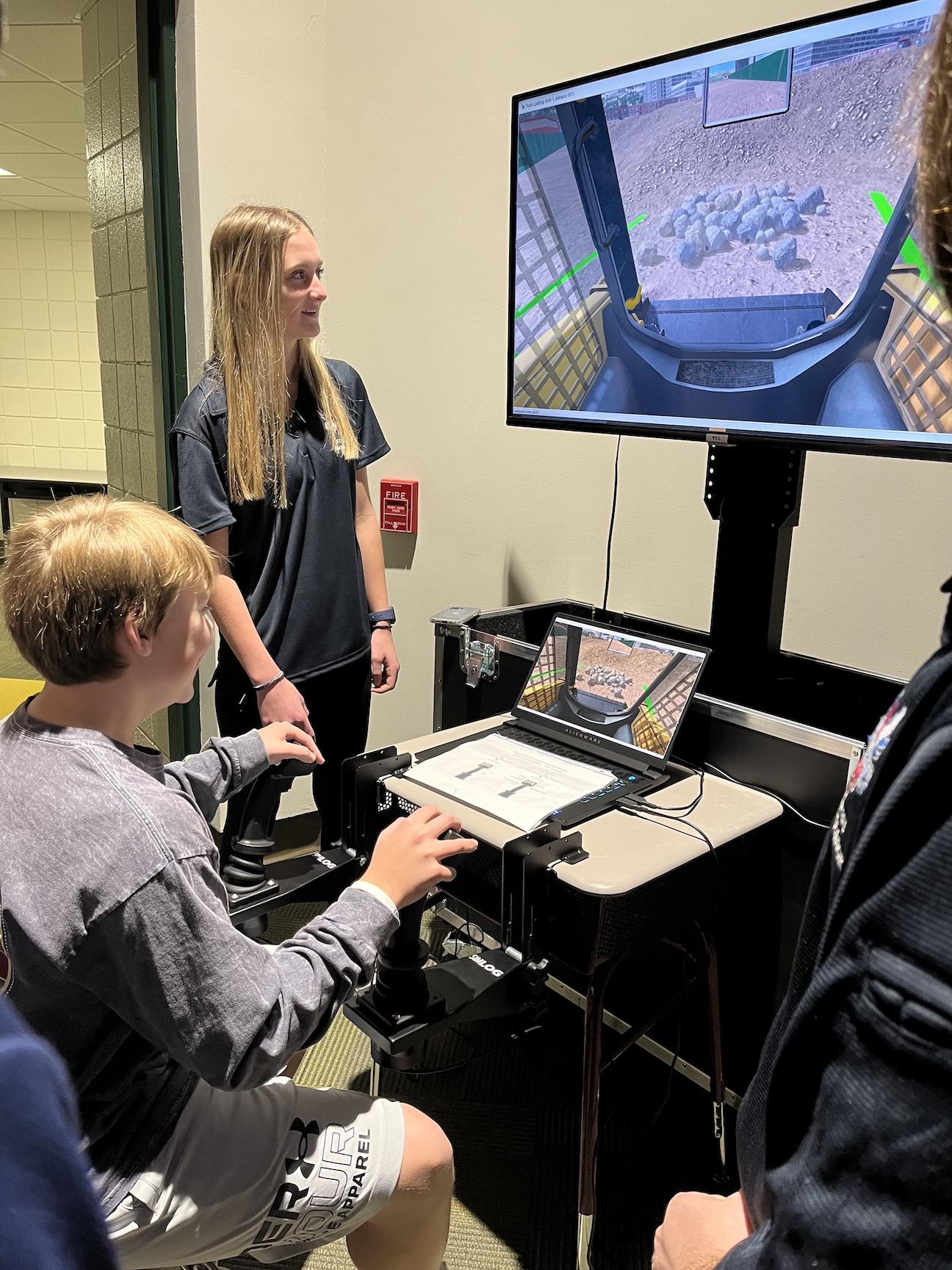 Ambassador Emily Painter guides a student using one of the simulators